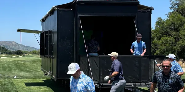 Mobile golf simulator trailer expanded at an outdoor event