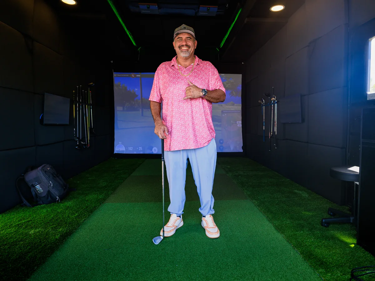 Daren Kawika Martin standing on the turf inside the climate-controlled trailer bay, club in hand
