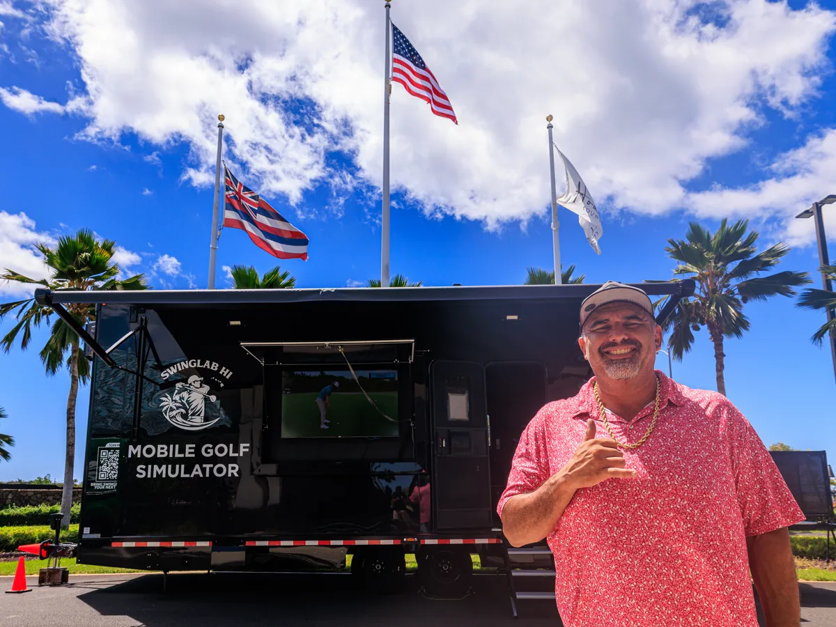 Daren Kawika Martin throwing a shaka beside the wrapped SwingLab Hawaii trailer on Oahu