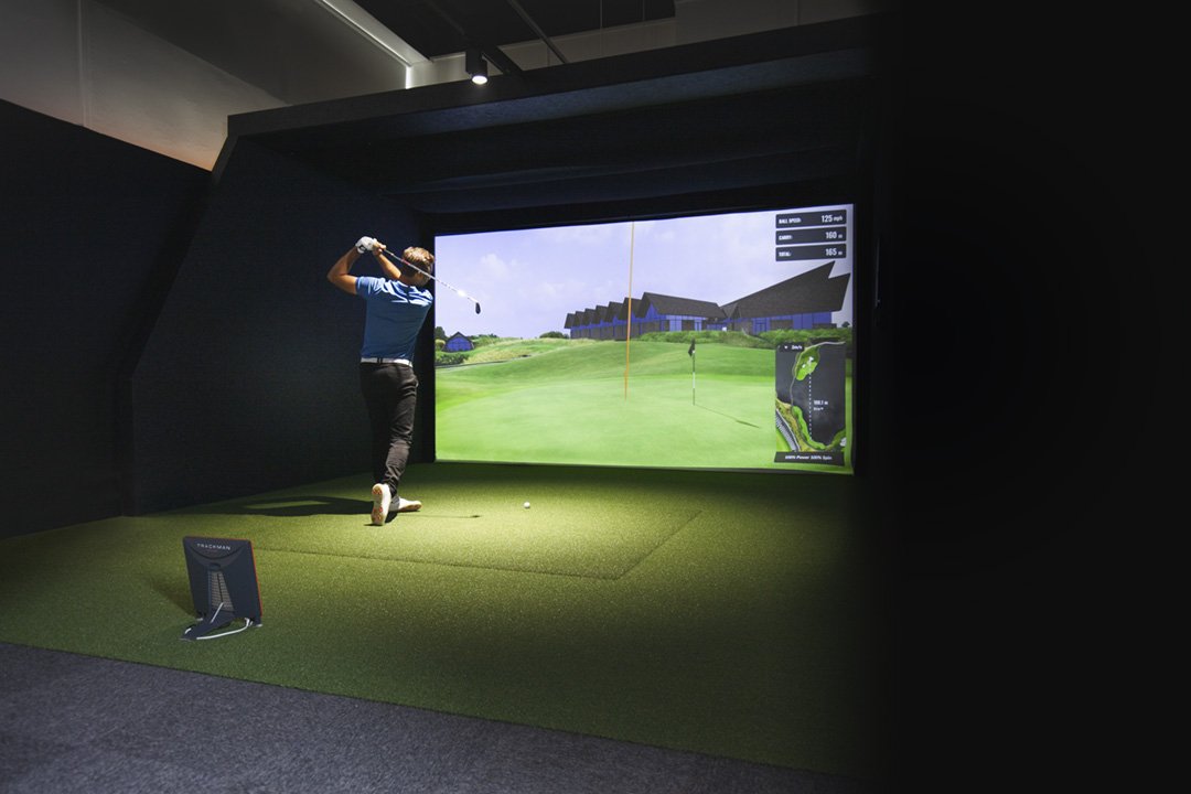 A player swinging inside a TrackMan simulator setup